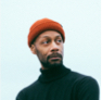 A head shot of gentleman with a yellow hat and green shirt