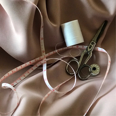 Scissors measuring tape and spring laying on a pink textile