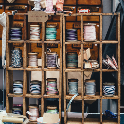 A bunch of spooled up ribbons sitting on different levels of a shelf